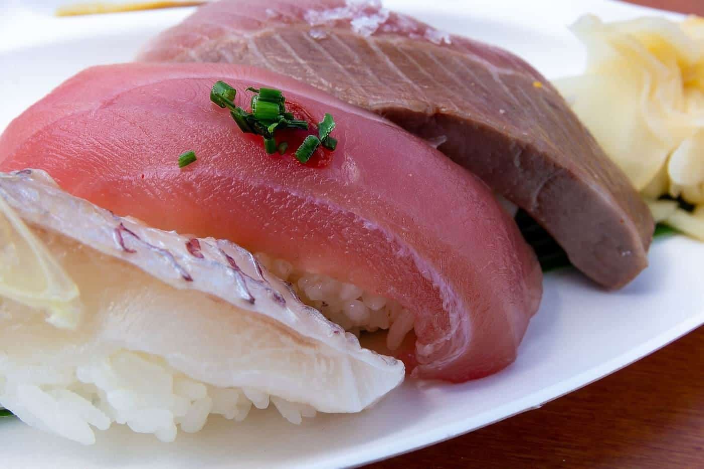 A platter of sliced sashimi on ice with garnishes